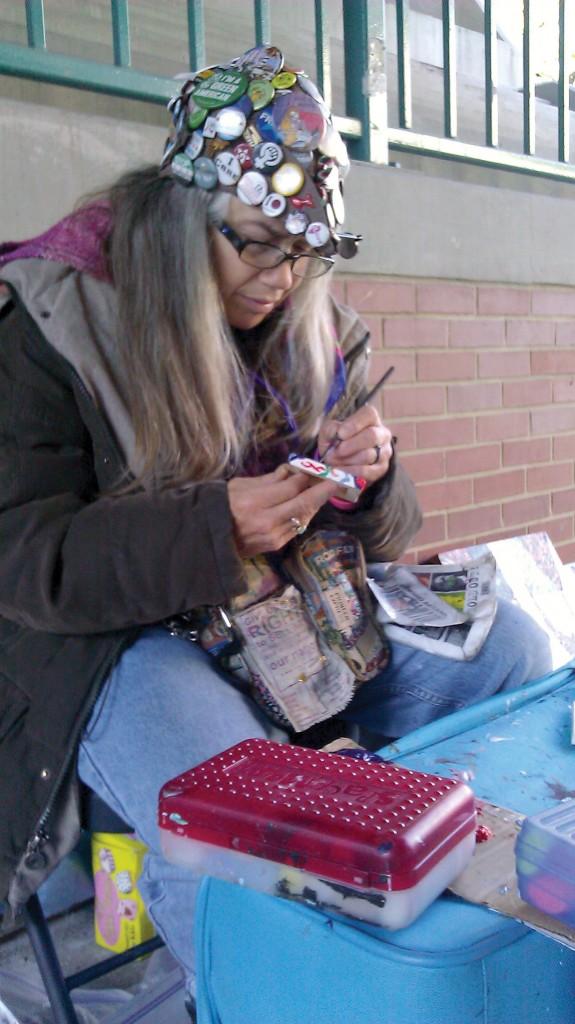 Homeless artist Betsy Benefield sells abstract calligraphy paintings under the Davis El stop to support herself.