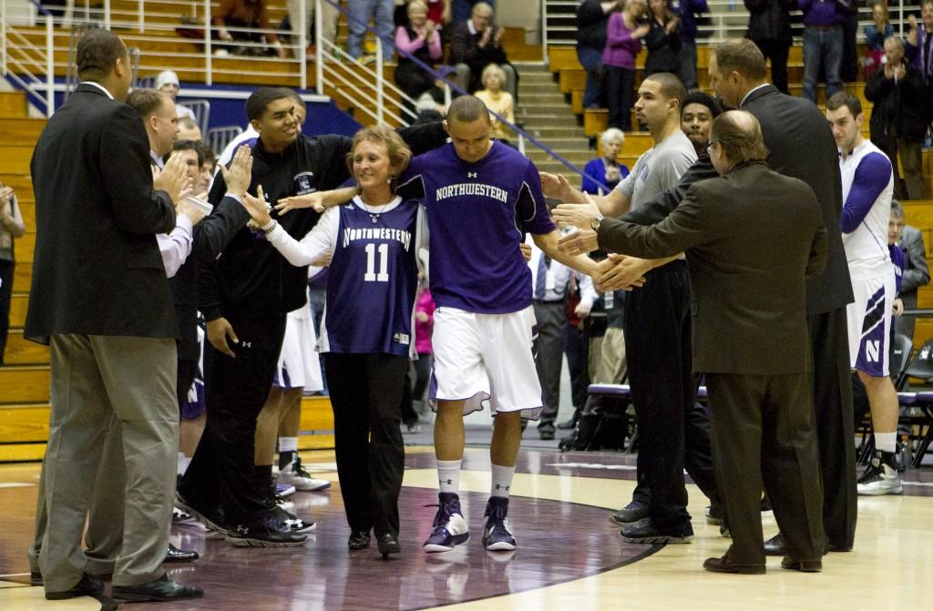 Senior guard Reggie Hearn high fives teammates as he walks onto the court with his mother during Senior Night at Welsh-Ryan Arena.