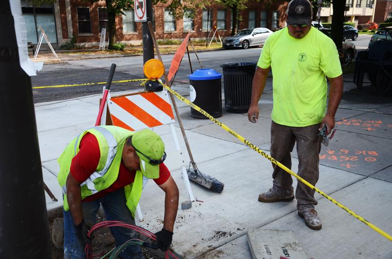 Oscar Gutierrez (left) and Julio Gasca add wiring to a lamp post on the corner of Davis Street and Oak Avenue. Gasca said the city will use the wiring for festival lighting.