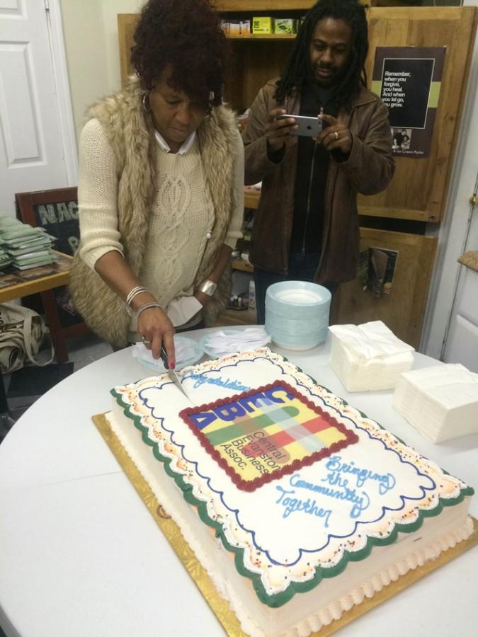 Brigitte Giles, owner of Ebony Barber Shop, cuts the cake to celebrate the Central Evanston Business Association Open House. Giles, also the president of CEBA, said she believes the organization will help develop central Evanston.
