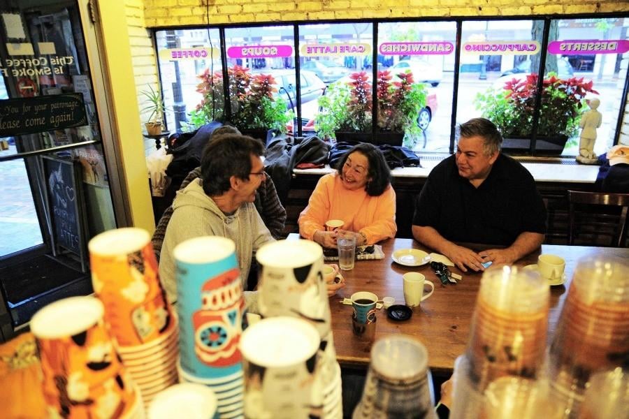 Darush Mabadi, Katherine Week and Bob Hariman sit at a communal table in Unicorn Cafe discussing politics and literature. They are part of a larger group of about 15 people who have been meeting daily for more than 25 years.