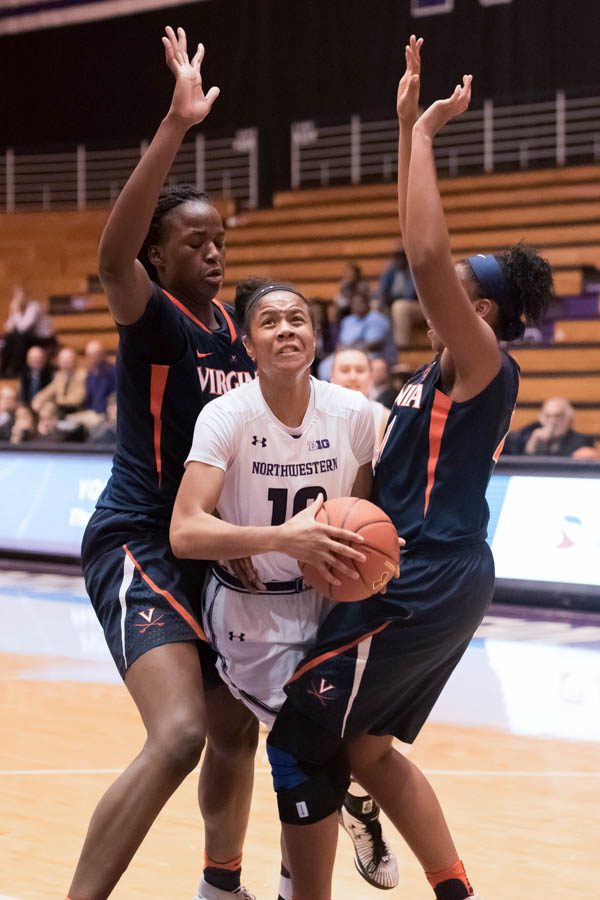 Nia Coffey fights through a pair of defenders in the post. The senior forward had another huge game to lift Northwestern past Virginia.