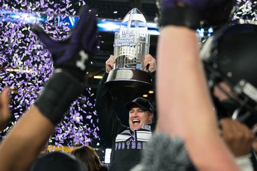 Coach Pat Fitzgerald raises the George Steinbrenner Trophy after Northwesterns Pinstripe Bowl victory. Fitzgerald is the first coach in program history to win two bowl games.