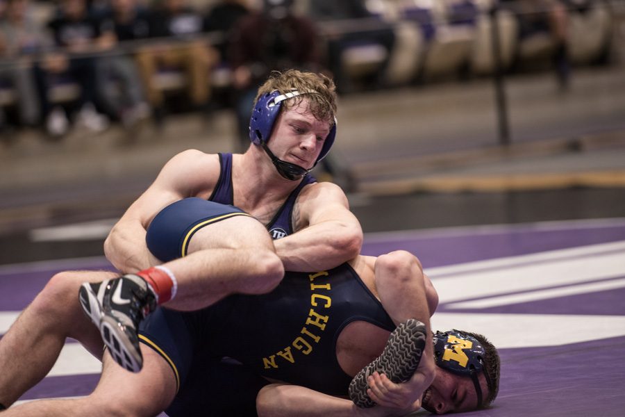 Jacob Berkowitz wrestles his opponent on the mat. The senior secured a comeback win in his final game at Welsh-Ryan Arena.