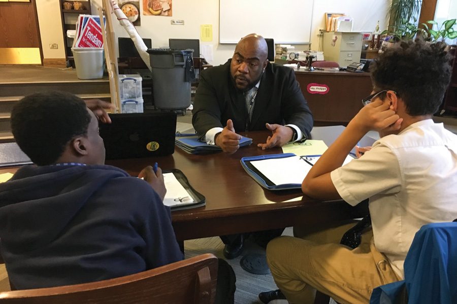 Nichols Middle School Principal Adrian Harries talks with two students in the Officer and Gentlemen Academy about the business plans they created. The students learned about business and entrepreneurship as a part of their weekly class Wednesday.