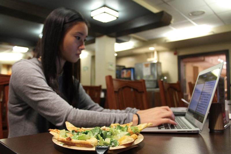 A student eats and works at Frans Cafe. Northwestern has instituted several new dining policies for next year.