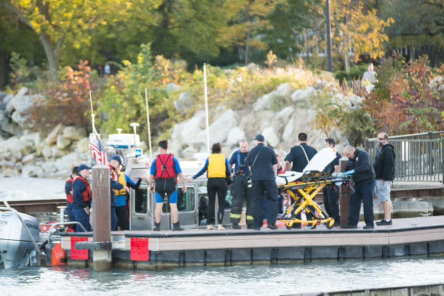 U.S. Coast Guard officers assist passengers Wednesday on a dock by Dempster Street Beach. Local safety forces responded after receiving a call that three individuals had fallen into the water once two boats collided. 
