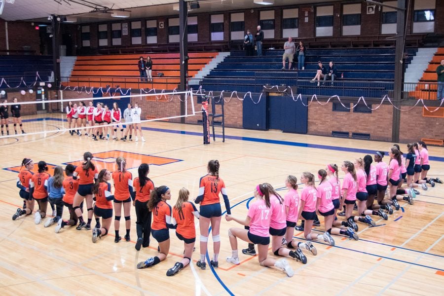 The Evanston Township High School girls varsity volleyball team kneels for the national anthem at an Oct. 11 home game in Beardsley Gym. Since then, other ETHS students followed in the team’s footsteps, including those on the boys varsity soccer team, football team and marching band. 
