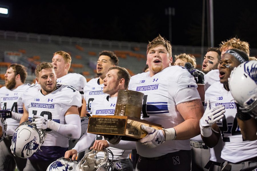 Tyler Lancaster celebrates with the Land of Lincoln trophy after Northwestern’s 42-7 victory over Illinois. The Wildcats will learn their bowl destination on Sunday.