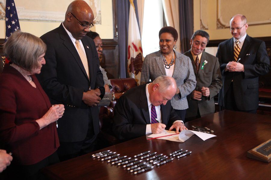 Former Gov. Pat Quinn, center, signs into law a bill ending the death penalty in Illinois in March 2011 at the State Capitol in Springfield with Kwame Raoul beside him. Quinn and Raoul are both democratic candidates for the March attorney general primary. 