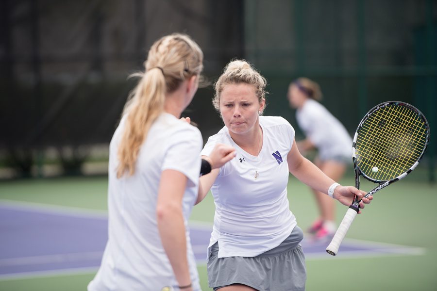 Maddie Lipp and Alex Chatt fist bump after a point. The seniors hope to lead an experienced NU squad heading into the 2018 dual match season.