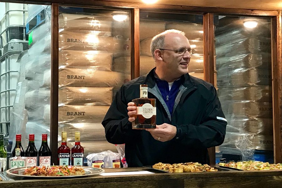 Steve Hagerty presents the Kentucky bourbon he won in a bet with Lexington Mayor Jim Gray. The event was hosted at FEW Spirits, an Evanston distillery. 