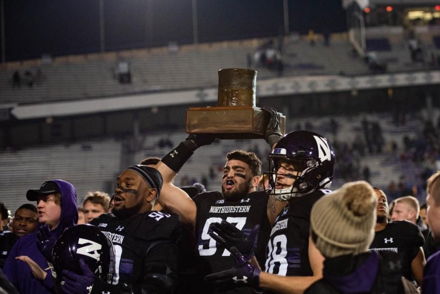 Junior defensive end Joe Gaziano hoists the Land of Lincoln Trophy among his teammates after Northwesterns 24-16 win over rival Illinois at Ryan Field on Saturday.