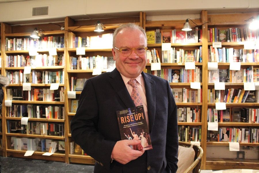 Chris Jones poses with his book “Rise Up!” at a Bookends & Beginnings event. Jones’ book charts works of American theatre that have influenced present-day society like “Hamilton.”