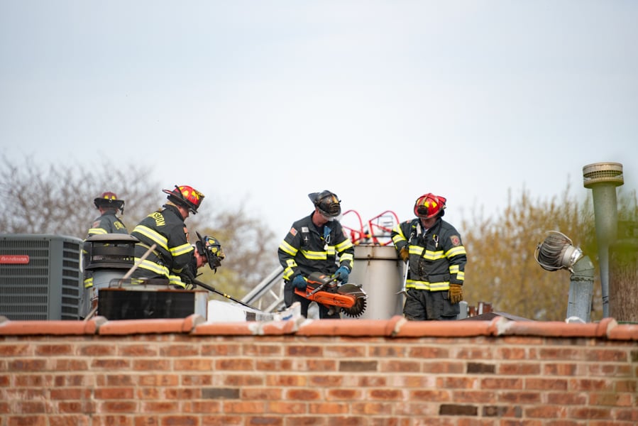 Evanston firefighters use a fire rescue saw and large Halligan bars to open the roof of the apartment building at 1740 Hinman Ave. EFD responded to a fire at the complex Wednesday at 4 p.m. 