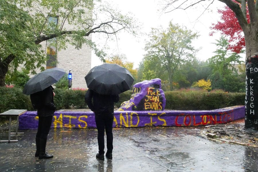 Passersby view the Rock, which was painted Homecoming weekend and criticized Northwestern’s inaction following student demands to remove University founder John Evans’ name from campus buildings.