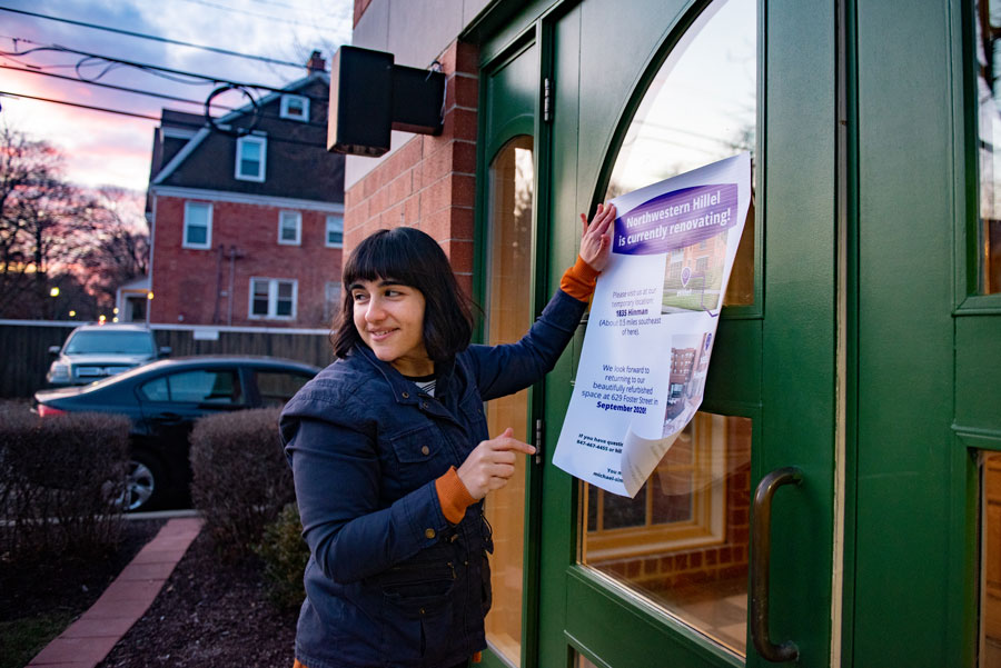 Rebecca Haas puts up a sign at Hillel’s 629 Foster St. building announcing its temporary relocation to 1835 Hinman amid renovations.