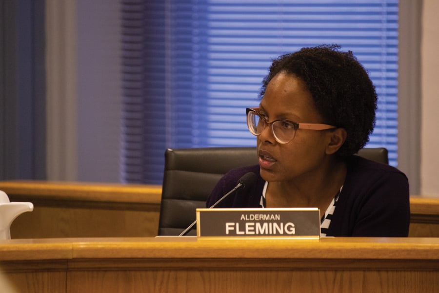 Alderwoman Cicely Fleming sits at a city council meeting and speaks into a black microphone