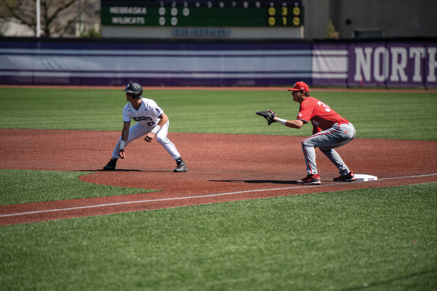 Men’s player Michael Trautwein crouches on the basepath, leading off from first base.