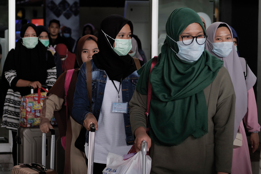 Airline passengers at the airport in Cengkareng, Indonesia wearing face masks to protect themselves from the outbreak of the novel coronavirus on Saturday, Feb. 1, 2020.