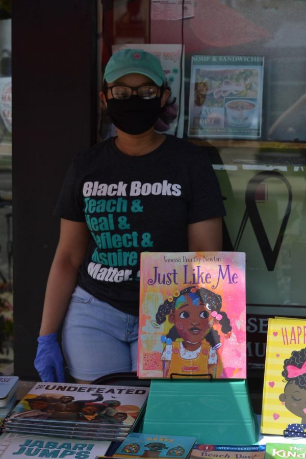Krenice Roseman, founder of Young, Black, and Lit stands in front of children’s books they are giving away for free as part of a pop up at C&W. 