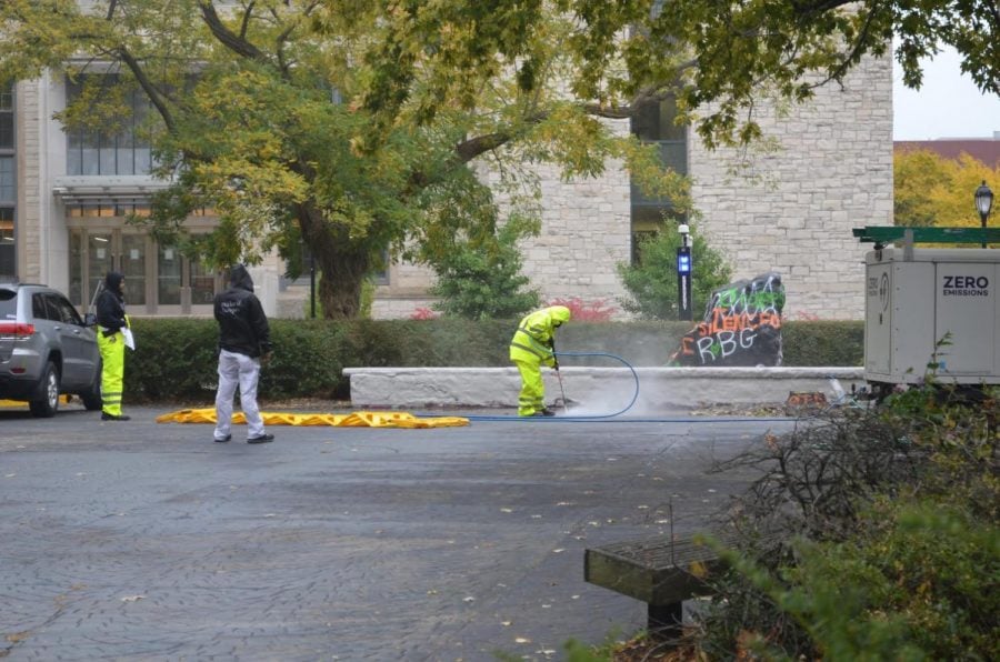 Members of the Facilities team pressure wash messages painted around The Rock.
