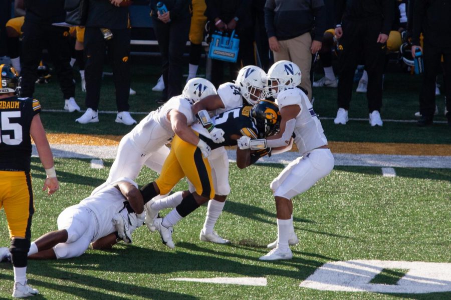Three Wildcats team up for a tackle. NU held Iowa to 104 total yards in the second half. 