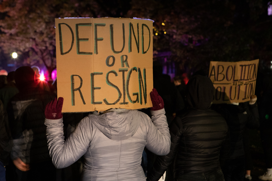 One+demonstrator+holds+up+a+sign+reading+%E2%80%9CDefund+or+Resign%E2%80%9D+at+Monday+night%E2%80%99s+march.%0A