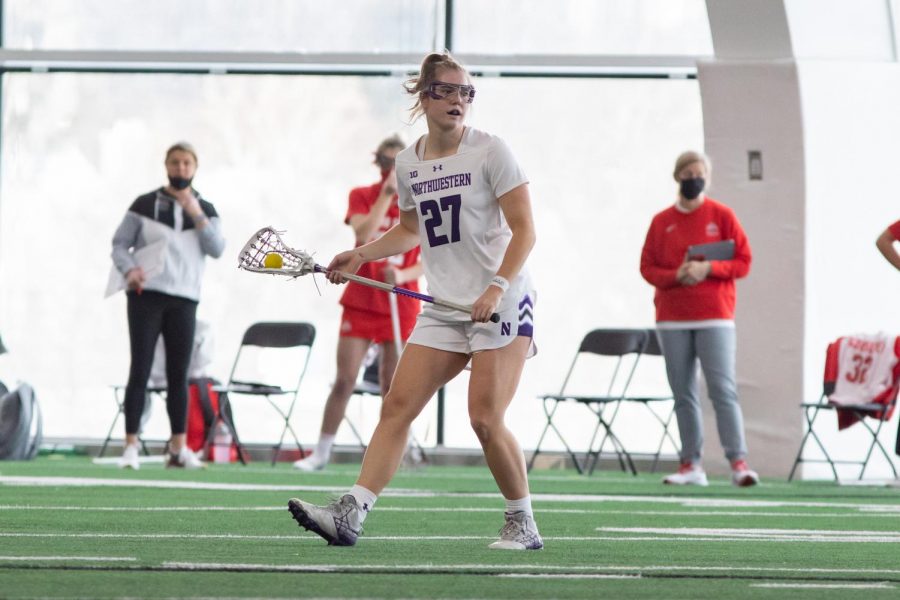 Northwestern+lacrosse+player+holds+a+stick+horizontally+on+the+field.