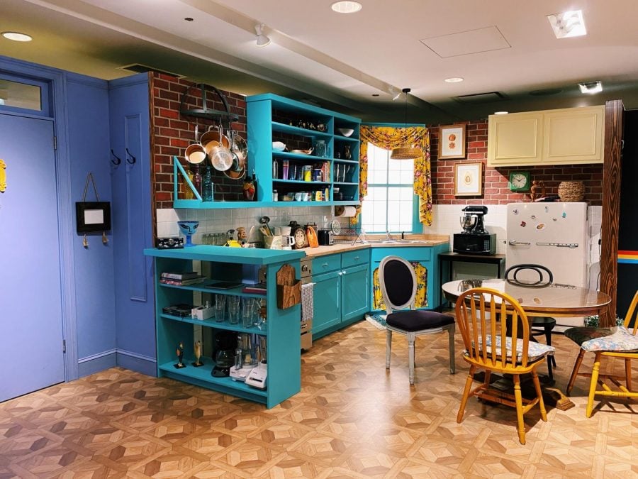 Apartment kitchen, showing purple door on the left, blue counters and dining table with chairs.