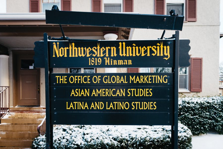 A black sign outside of a beige house. The sign states, from top to bottom, “Office of Global Marketing, Asian American Studies, and Latina and Latino Studies.”