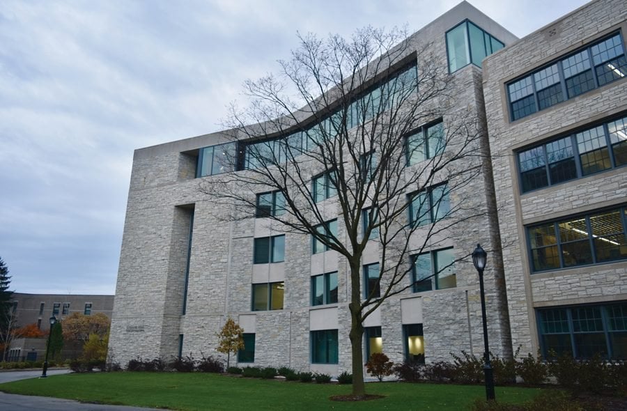 A photo of a multi-story grey brick building, towering over a tree on Northwesterns campus.