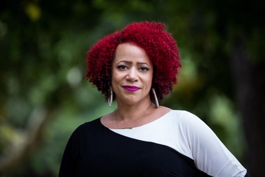 Nikole Hannah-Jones stands in a black and white shirt against a green background.