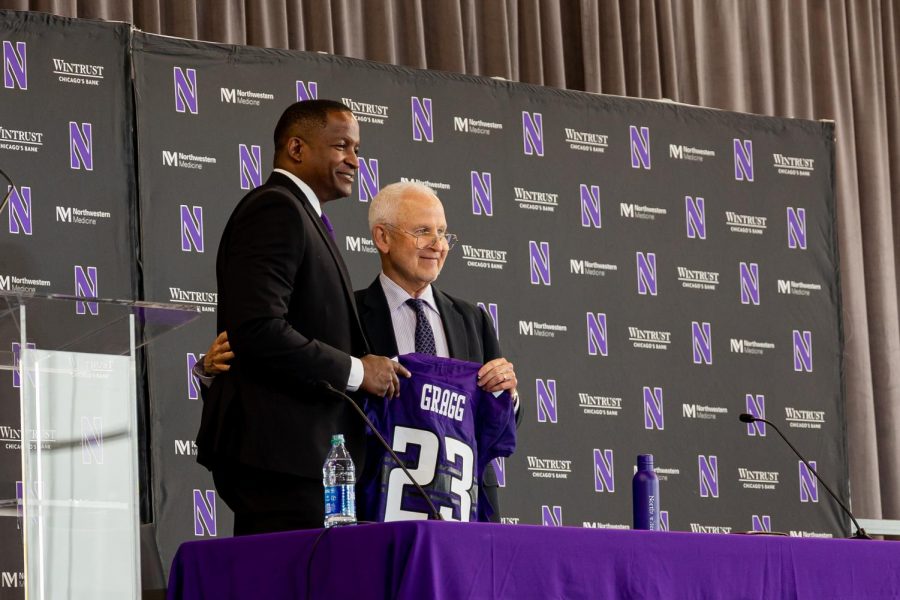 Two+men+in+suits+hold+a+purple+jersey+with+No.+23+and+the+name+Gragg+on+it%2C+standing+in+front+of+a+black+poster+with+the+Northwestern+logo+and+the+words+Wintrust.