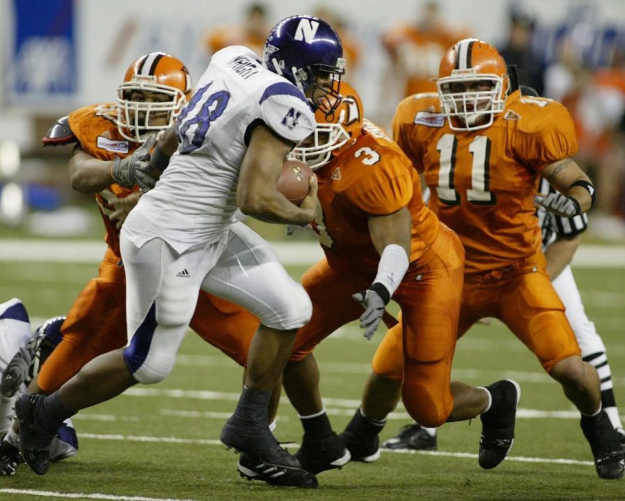 A running back carries the football against three defenders.