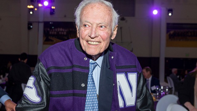 Howard+Trienens+wears+a+Northwestern+letterman+jacket+and+a+blue+checked+collared+shirt.