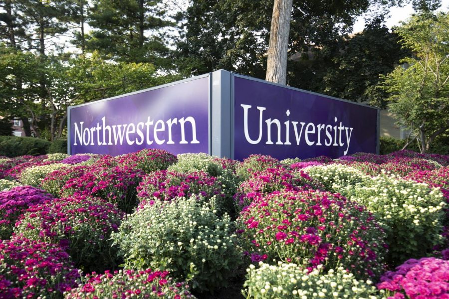 A large Northwestern University sign sits amid pink and white flowers.