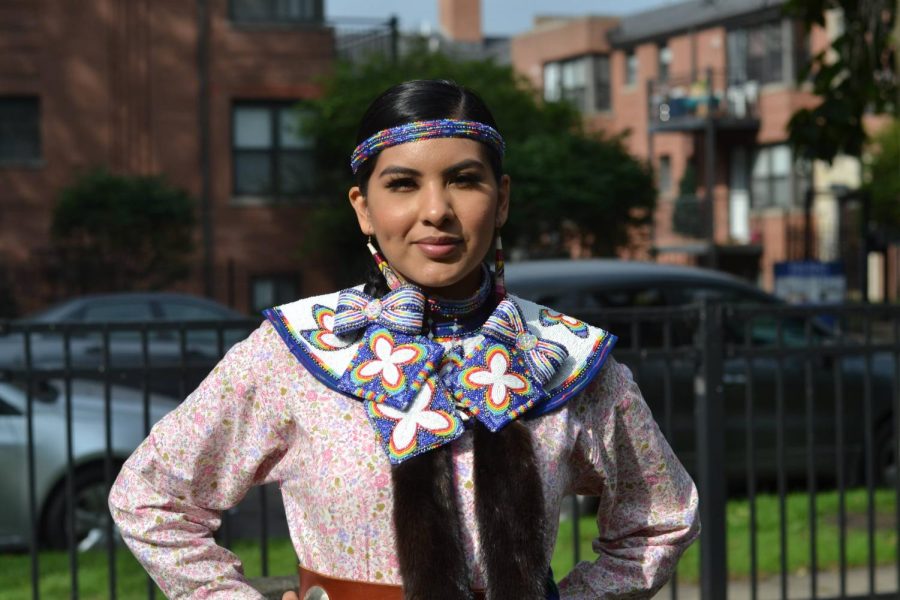 Marissa Garcia, a member of the Mississippi Band of Choctaw Indians. She stands wearing a traditional dress she made herself, including handmade beadwork, sewing and tobacco tin tops adorned onto the skirt that jingles while she dances.