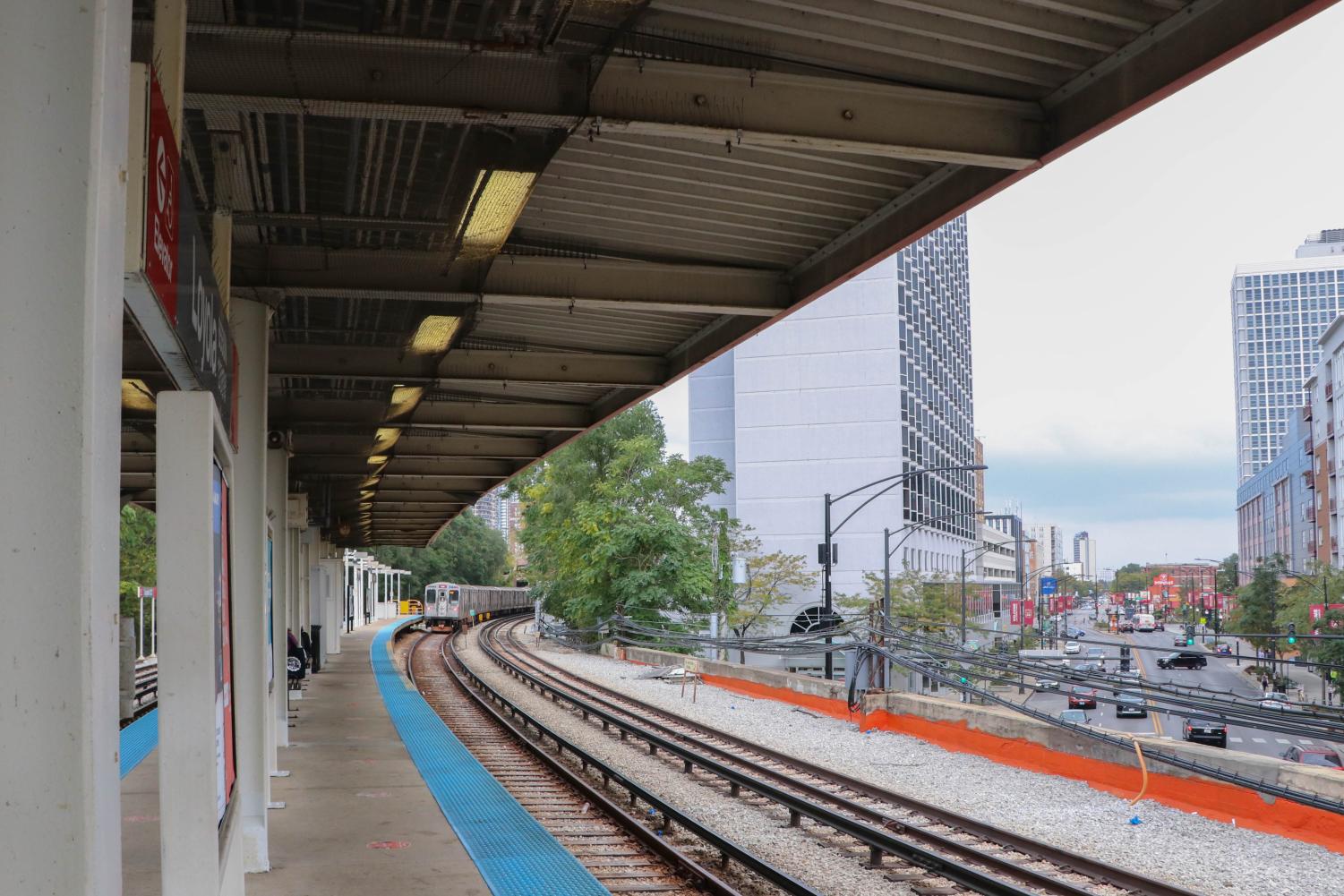 A+distant+train+rolls+into+the+Loyola+CTA+station.+City+buildings+are+visible+in+the+distance.