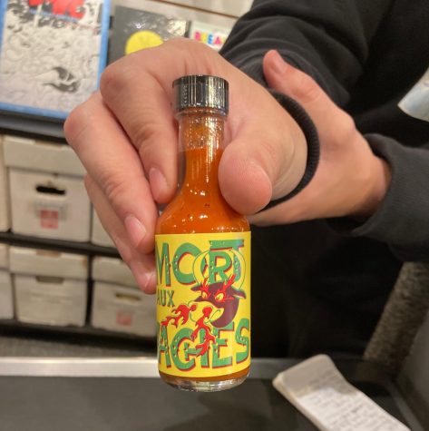Comix Revolution sales associate Frank Rodriguez holds a bottle of craft hot sauce commemorating the company’s 25th anniversary. The bottle reads “Mort Aux Vaches” (Death to Cows), with “Mort” being a nod to president Jim Mortensen’s name.