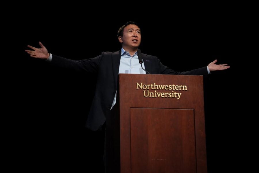 Andrew Yang, with his arms outstretched, at a podium in Cahn Auditorium