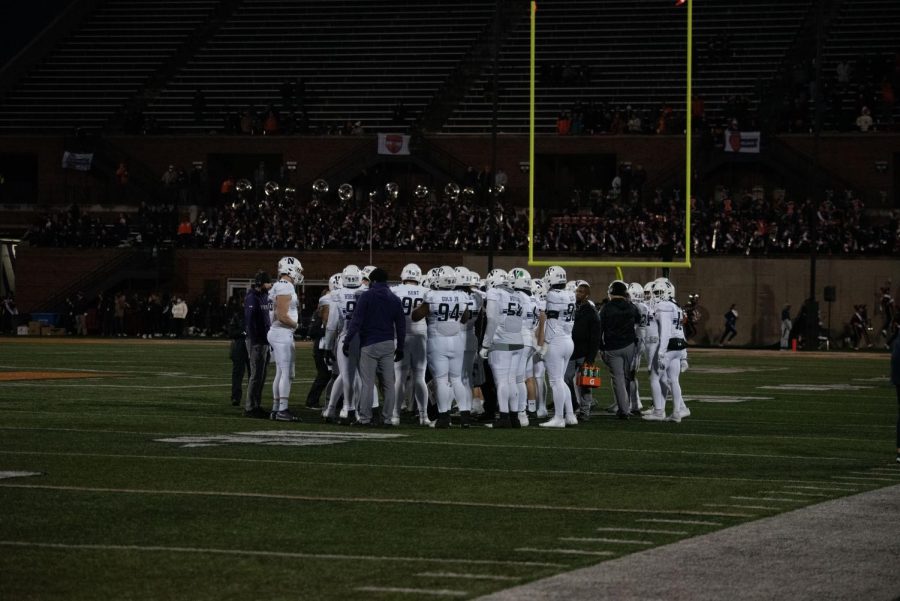 Players in white jerseys stand on green field