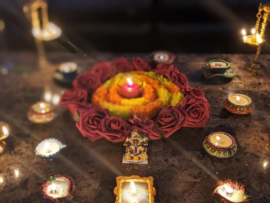 A+red+diya+sits+in+the+center+of+the+frame%2C+surrounded+by+a+ring+of+flowers+and+lights.