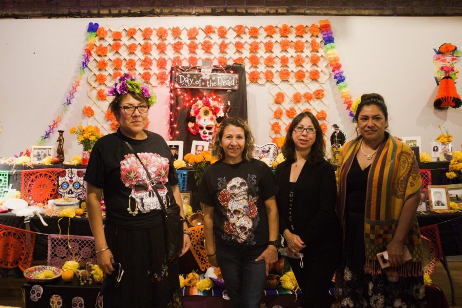 Four people standing in front of a colorful altar with skulls and tissue paper decorations. Credit: Dylan Wu/The Daily Northwestern