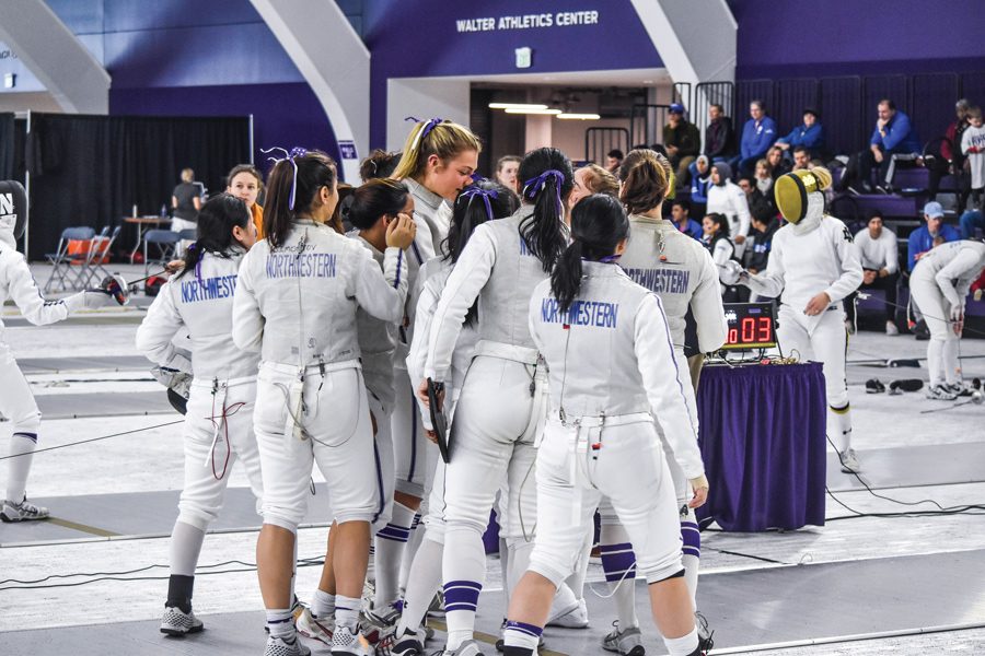 The+fencing+team+huddles+together+in+a+celebration+after+a+bout+at+the+2021+NCAA+Championships.