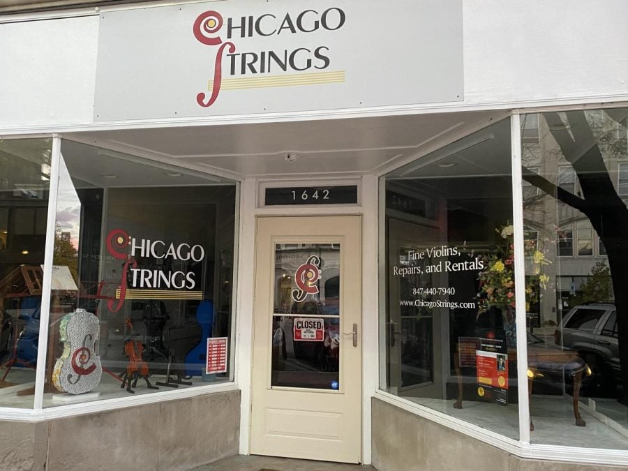 The storefront for Chicago Strings has the logo of the business with music notation graphics, as well as decorative violins in the window.