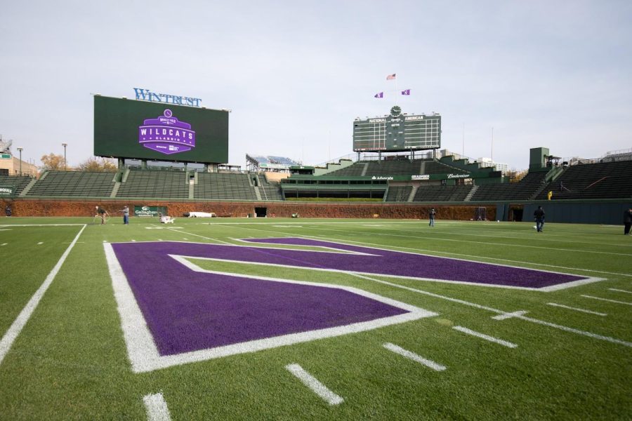 A purple “N” painted on a football field, with a large jumbotron and green scoreboard in the background. 