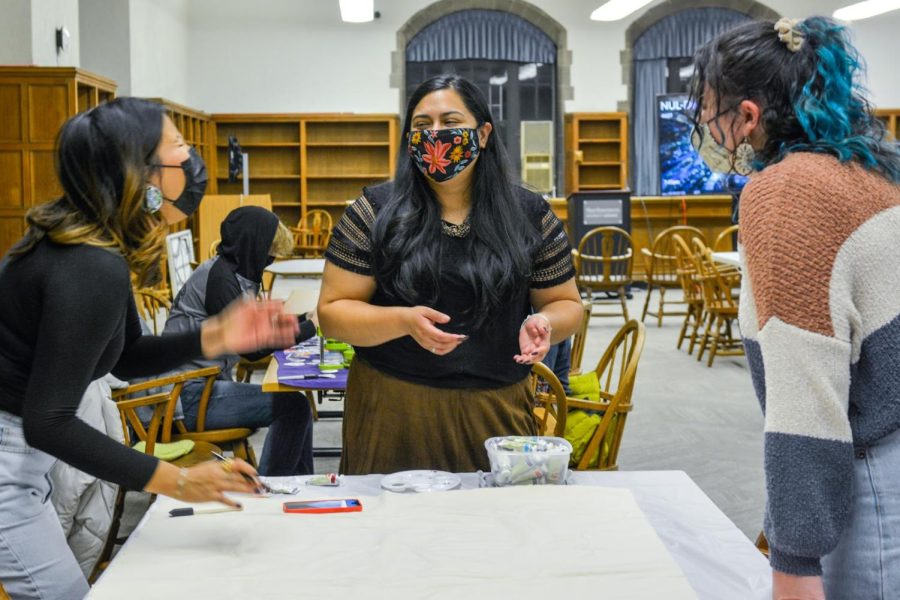 Three people standing around a table in Deering Library with art supplies.
