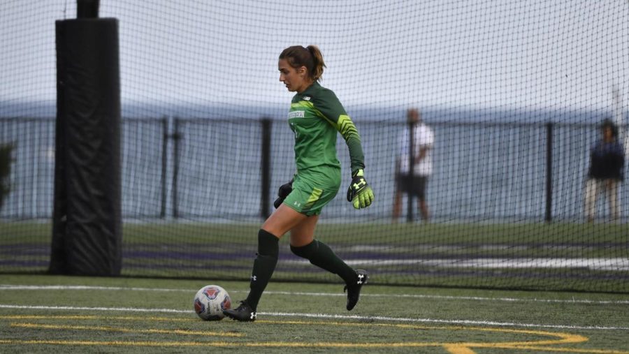 Mackenzie Wood, dressed in her lime green, long-sleeved jersey, prepares to kick the soccer ball down the field by the water.
