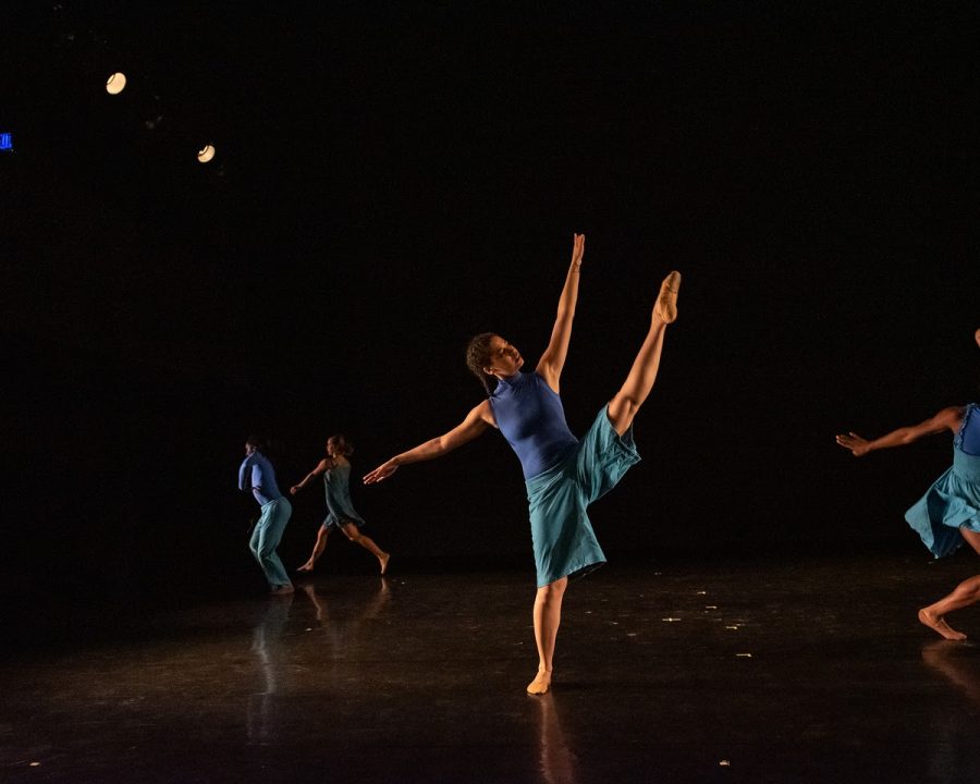 Jacinda Ratcliffe, in blue, dancing in one of her recent shows with one leg in the air.